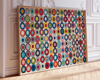 Può includere: Un'opera d'arte incorniciata con un motivo astratto e colorato di cerchi sovrapposti in varie dimensioni e tonalità, tra cui rosso, blu, giallo e verde. L'opera è ambientata su uno sfondo color crema e incorniciata in legno chiaro.