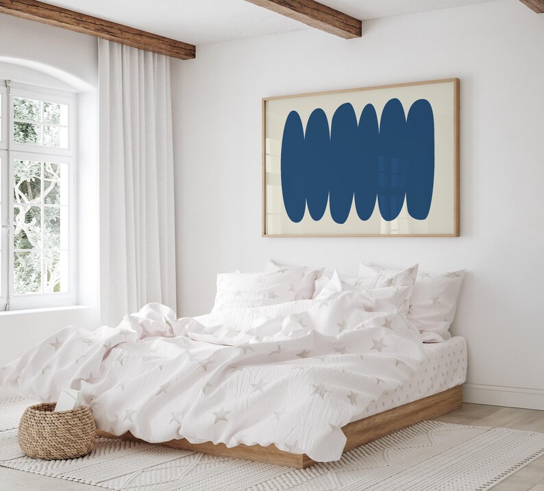 May include: A white bed with a pink duvet cover and white pillows. The duvet cover has a subtle star pattern. A framed print with a blue abstract design hangs on the wall above the bed.
