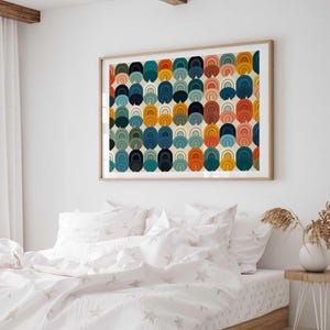 May include: A rectangular wall art print in a light wood frame featuring a repeating pattern of stacked semi-circular arches in shades of navy blue, teal, mustard yellow, terracotta orange, and soft pink on a cream background.