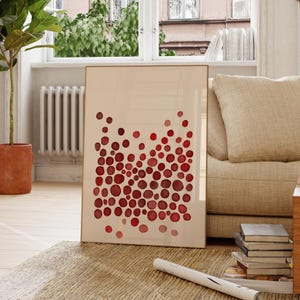 May include: A rectangular framed wall art print featuring a light beige background with a dense cluster of circular shapes in varying shades of red. The circles are arranged in a vertical pattern, with some appearing darker and others lighter in color.