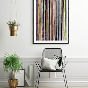 Pu&ograve; includere: Una stampa incorniciata nera di un design astratto colorato fatto di strisce verticali di vari colori e trame. La stampa &egrave; appesa a un muro bianco sopra una sedia in metallo nero con un cuscino bianco.