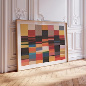 Puede incluir: Una impresión de arte mural rectangular enmarcada que presenta una cuadrícula de bloques multicolores en tonos amarillo, rojo, azul, verde, gris y marrón. La obra está dentro de un marco de madera clara, mostrando un patrón geométrico de rectángulos.