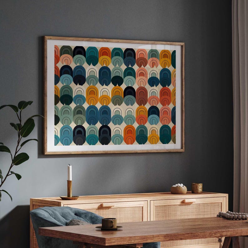 May include: A rectangular wall art print in a light wood frame featuring a repeating pattern of stacked arch shapes in shades of orange, teal, navy blue, and soft pink against a cream background, displayed in a horizontal orientation.