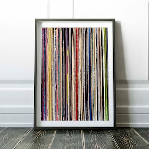 Pu&ograve; includere: Una stampa incorniciata di un muro di dischi in vinile colorati. I dischi sono disposti verticalmente in una griglia. La cornice &egrave; nera e lo sfondo &egrave; bianco.
