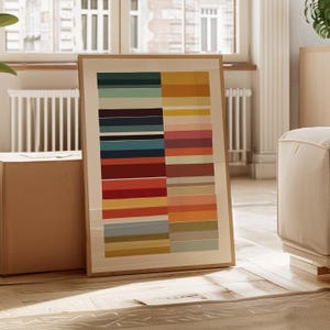 Puede incluir: Una impresi&oacute;n art&iacute;stica abstracta enmarcada con una serie de rayas horizontales de colores. La obra de arte presenta una paleta de varios colores, incluyendo verde azulado, amarillo, rojo y naranja. La impresi&oacute;n est&aacute; en un marco de madera clara.