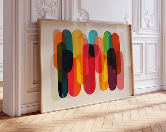 May include: A framed abstract art print featuring overlapping vertical shapes in vibrant colors. The artwork includes shades of red, orange, yellow, green, blue, and black. The frame is a light wood color, and the print is leaning against a white wall.