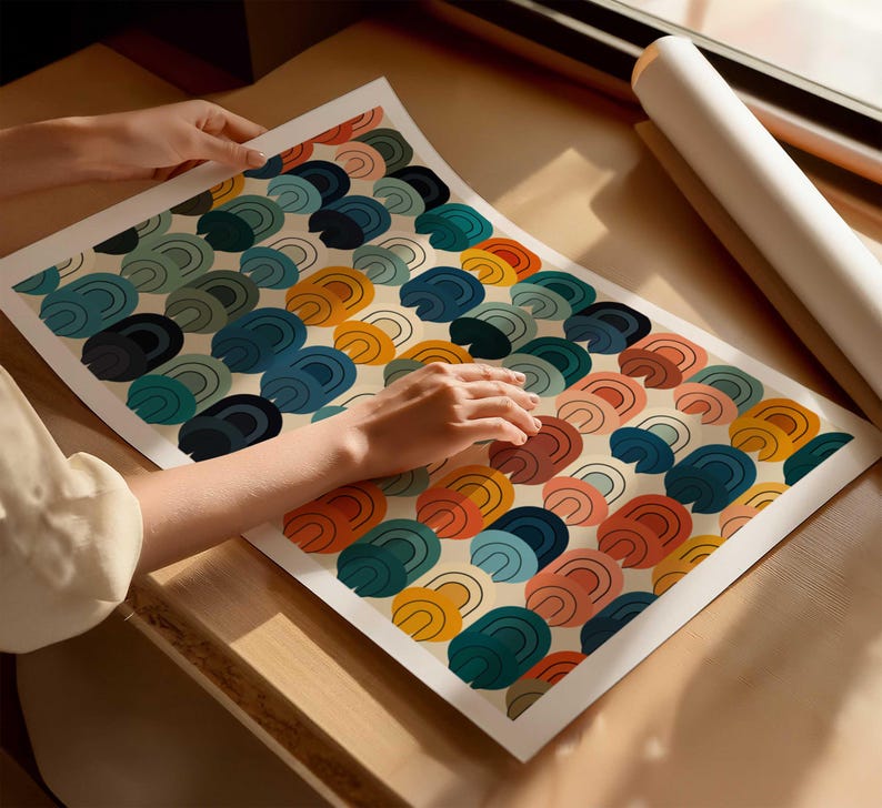 May include: A rectangular art print featuring a repeating pattern of stacked, semi-circular arch shapes in shades of mustard yellow, terracotta orange, teal, dark blue, and soft pink, all set against a light cream-colored background.