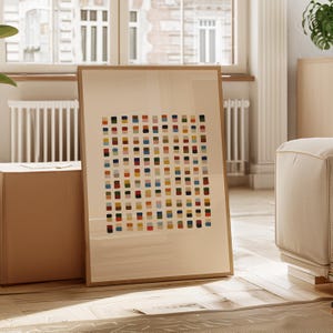 May include: A rectangular framed wall art piece featuring a grid of small, multicolored squares in shades of blue, red, yellow, green, and pink against a light beige background. The artwork is enclosed in a simple, light-toned wooden frame.