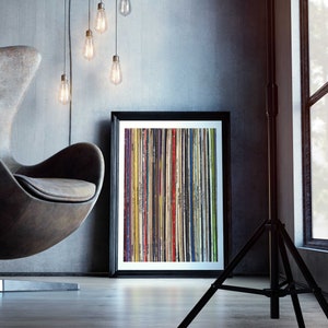 Pu&ograve; includere: Una stampa incorniciata di un design astratto colorato con strisce verticali di vari colori e trame. La stampa &egrave; appesa a una parete grigia in un ambiente di soggiorno moderno.