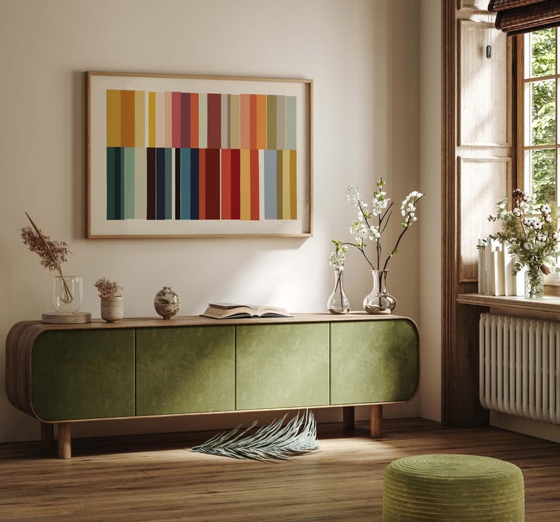 Puede incluir: Un sal&oacute;n moderno con un mueble verde de terciopelo con patas de madera, una obra de arte abstracta enmarcada con rayas verticales coloridas y jarrones decorativos con flores. La habitaci&oacute;n tiene un ambiente c&aacute;lido y acogedor.