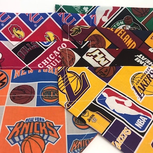 May include: A stack of colorful fabric squares with different NBA team logos, including the New York Knicks, Chicago Bulls, Los Angeles Lakers, Cleveland Cavaliers, and Miami Heat. The fabric is a patchwork of different colors and patterns, including red, blue, yellow, green, and black.