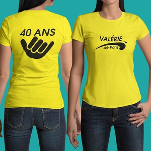 Puede incluir: Dos camisetas amarillas. Una camiseta tiene el texto "40 ANS" y un gráfico de gesto de mano en la espalda. La otra camiseta tiene el texto "VALERIE de Paris" en negro. Ambas camisetas son de manga corta.