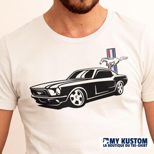 Op de afbeelding: Wit T-shirt met een zwart-witte illustratie van een klassieke Ford Mustang. De auto heeft een renpaardlogo erboven met rode, witte en blauwe strepen.