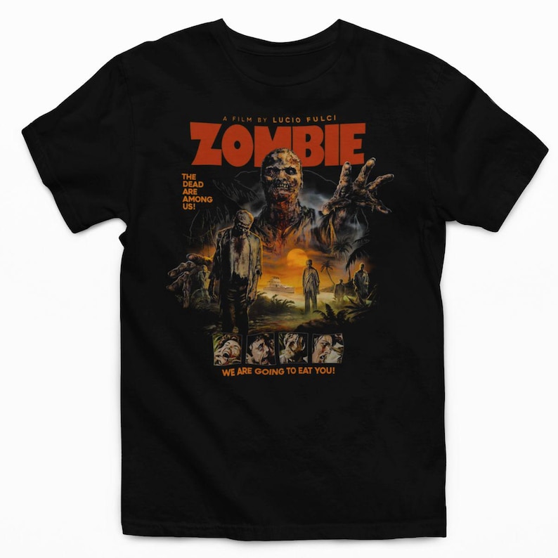 Puede incluir: Una camiseta negra con un estampado gr&aacute;fico del p&oacute;ster de la pel&iacute;cula A Film By Lucio Fulci Zombie. El dise&ntilde;o incluye un zombi grande, un paisaje de isla tropical y el texto The Dead Are Among Us y We Are Going To Eat You.