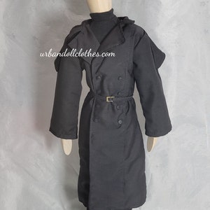 May include: A black trench coat with a double-breasted design, a belt, and a high collar. The coat is worn over a black turtleneck and pants, paired with black boots. The website urbandollclothes.com is visible on the coat.