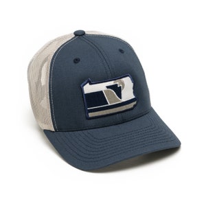 May include: Navy blue trucker hat with a beige mesh back and a curved brim. The hat features a patch with a stylized Pennsylvania state outline in white, navy, and gray. A button is on top of the hat.