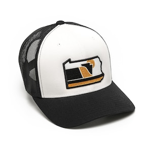 May include: A white and black trucker hat with a black mesh back. The front of the hat features a black and gold embroidered patch of the state of Pennsylvania.