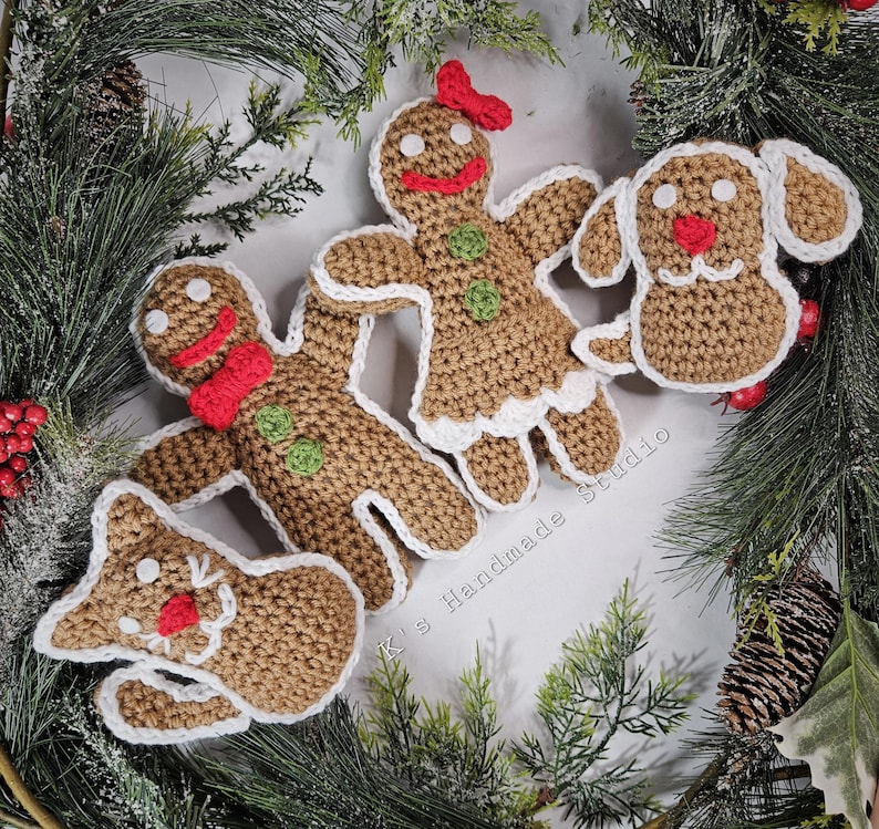 May include: Four crocheted Christmas ornaments: a gingerbread person, a gingerbread dog, a gingerbread cat, and a gingerbread woman. All are brown with white trim and red accents. The ornaments are arranged on a green pine branch background.