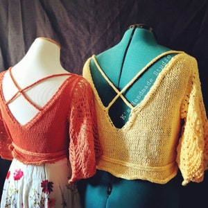 May include: Two crocheted tops with criss-cross straps in the back. The top on the left is orange and the top on the right is yellow. The text "K.S. handmade studio" is visible on the yellow top.