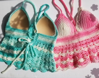 May include: Two crocheted tops, one in teal and white and the other in pink and white. Both tops have a scalloped hem and are made with a delicate crochet stitch.