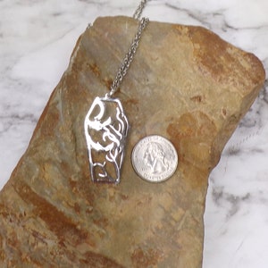 Pu&ograve; includere: Una collana d'argento con un ciondolo a forma di due mani intrecciate. Il ciondolo &egrave; circa delle dimensioni di una moneta da 25 centesimi di dollaro americano.