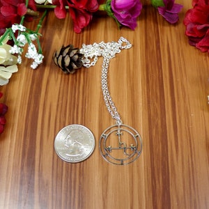 May include: Silver necklace with a circular pendant featuring a pentagram and the symbol 'L.V.X.', a common symbol associated with Luciferianism.