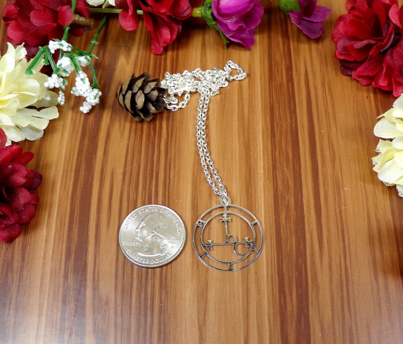May include: Silver necklace with a circular pendant featuring a pentagram and the symbol 'L.V.X.', a common symbol associated with Luciferianism.