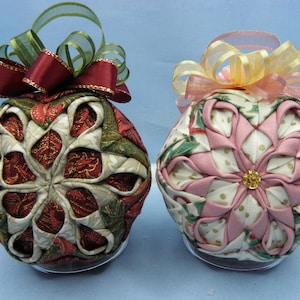 May include: Two handmade Christmas ornaments, one with a red and green floral pattern and a red bow, and the other with a pink and white floral pattern and a pink and yellow bow.