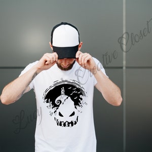 May include: A white t-shirt with a black silhouette of Jack Skellington's face from the movie "The Nightmare Before Christmas". The silhouette is surrounded by trees and birds. The person wearing the shirt is holding a black and white baseball cap.