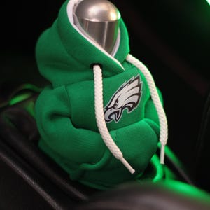 May include: Green and white hooded sweatshirt gear shift cover with the Philadelphia Eagles logo.