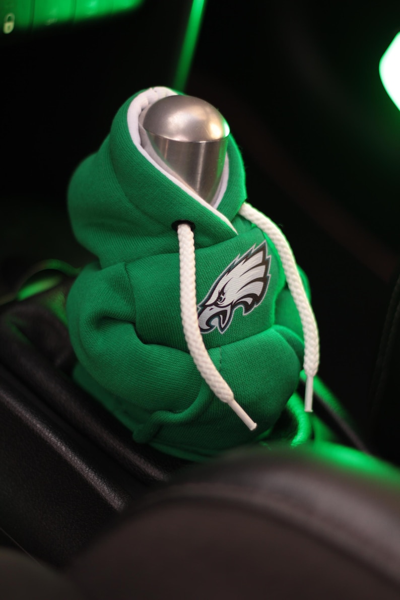 May include: Green and white hooded sweatshirt gear shift cover with the Philadelphia Eagles logo.
