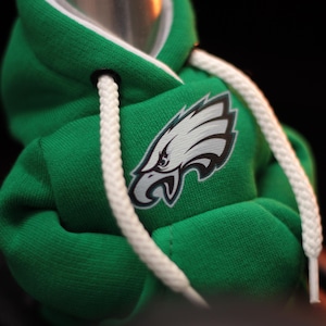 May include: Green hooded sweatshirt with a white drawstring and a white and teal eagle logo on the front.