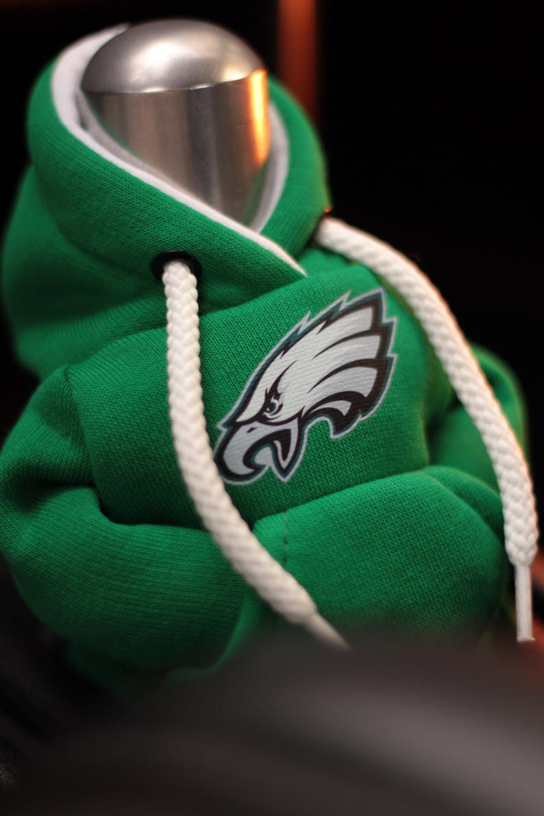 May include: Green hooded sweatshirt with a white drawstring and a white and teal eagle logo on the front.
