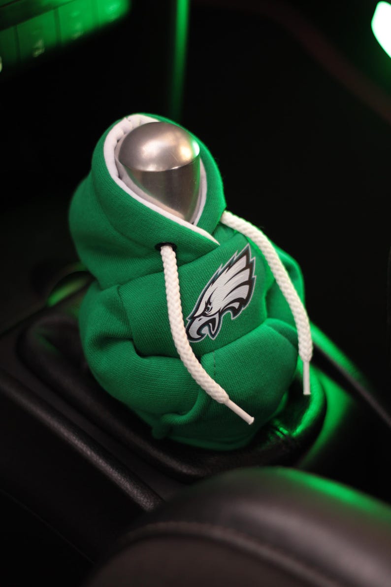 May include: Green and white hooded sweatshirt gear shift knob with a white eagle logo. The sweatshirt is made to look like a miniature hoodie.