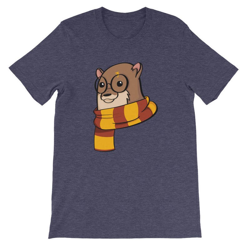 May include: A navy blue t-shirt featuring a cartoon otter wearing round glasses and a striped scarf in shades of yellow, orange, and red. The otter has a lightning bolt on its forehead. The shirt is a short-sleeved crew neck.
