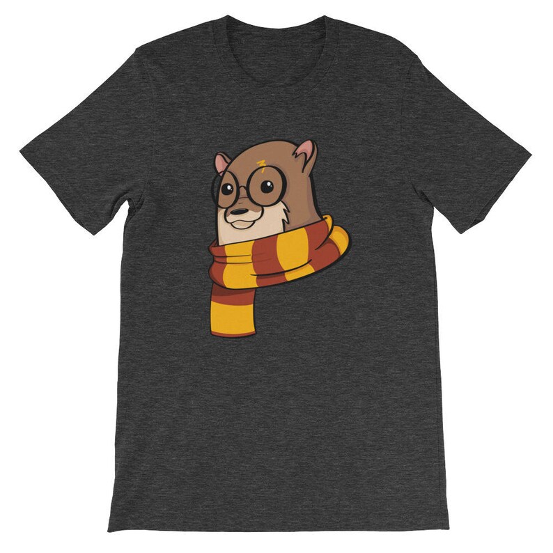 May include: Dark gray t-shirt featuring a cartoon otter wearing round glasses and a striped scarf in shades of yellow, orange, and red. The otter has a lightning bolt on its forehead. The shirt is a short-sleeved crew neck.