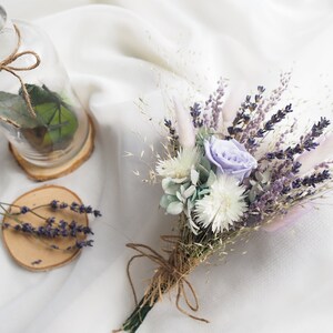 May include: A dried flower bouquet with a single purple rose, white flowers, and lavender sprigs tied with twine. The bouquet is on a white background.