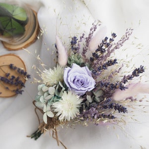 May include: A dried flower bouquet with a single purple rose, white flowers, lavender, and dried grasses.