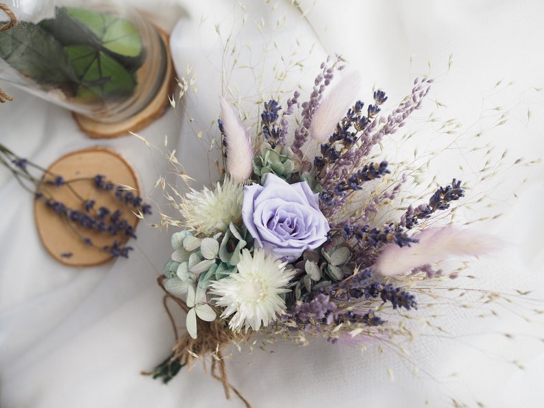May include: A dried flower bouquet with a single purple rose, white flowers, lavender, and dried grasses.