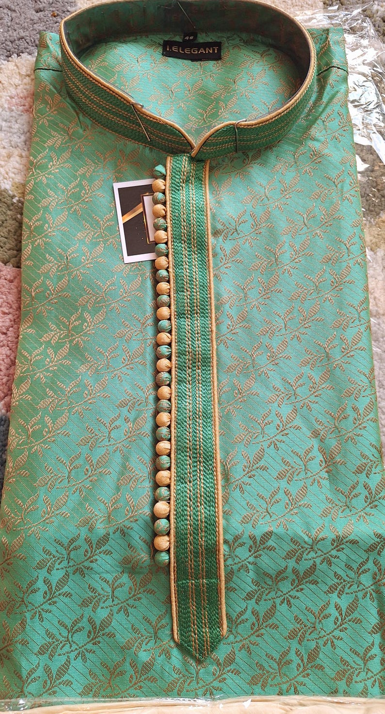 May include: A teal-colored kurta with a floral pattern and a mandarin collar. The neckline is accented with a green and gold trim and wooden beads. The label reads "i.ELEGANT".