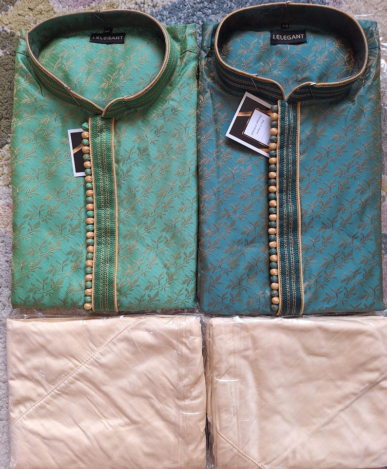 May include: Two silk kurta pajama sets. One is teal, the other is green, both with gold floral patterns. Each kurta has a mandarin collar and wooden bead accents. The matching pajama pants are a light beige color.