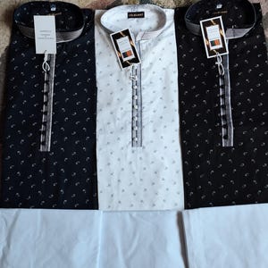 May include: Three long-sleeved shirts with matching white pants. Two shirts are black with a small white pattern, and one is white with a small black pattern. Each shirt has a mandarin collar and a button-down placket. The shirts have tags that read "ELEGANT".
