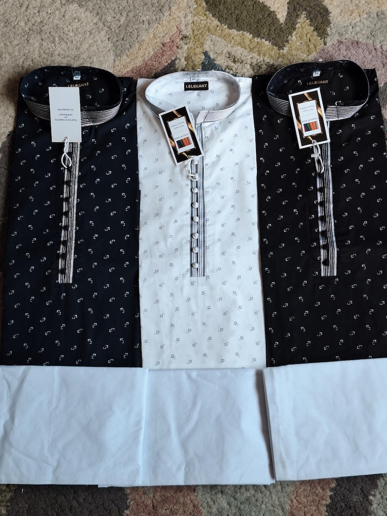 May include: Three long-sleeved shirts with matching white pants. Two shirts are black with a small white pattern, and one is white with a small black pattern. Each shirt has a mandarin collar and a button-down placket. The shirts have tags that read "ELEGANT".