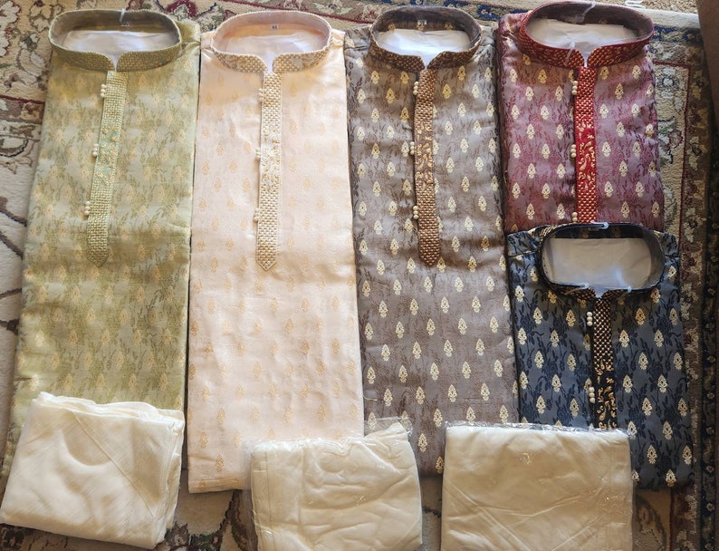 Op de afbeelding: Vijf verschillende gepatroneerde overhemden met bijpassende witte broeken. De overhemden zijn allemaal met lange mouwen en hebben een knoopsluiting. De patronen omvatten groen, beige, bruin, rood en blauw.