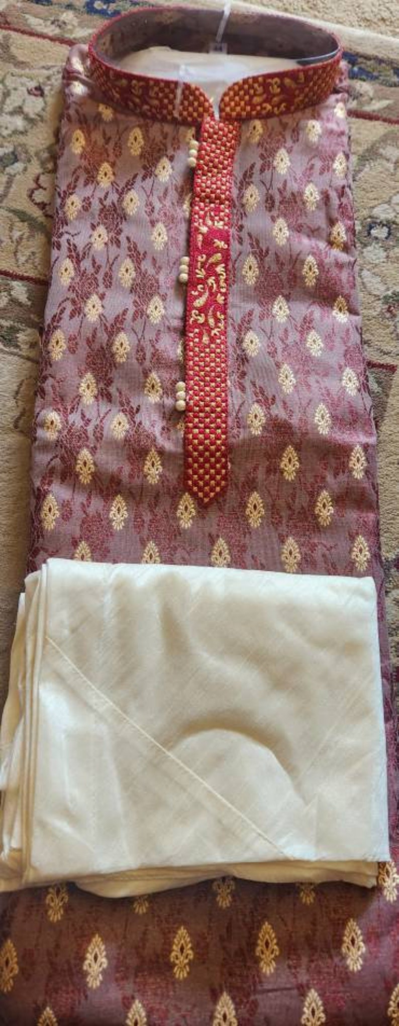 Op de afbeelding: Een maroon kurta met een witte kraag en een rood en gouden geborduurd ontwerp. De kurta wordt gecombineerd met een witte dupatta.