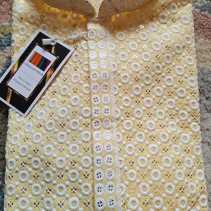 May include: A yellow kurta with white embroidery and a small tag that says "L Elegant Wear".