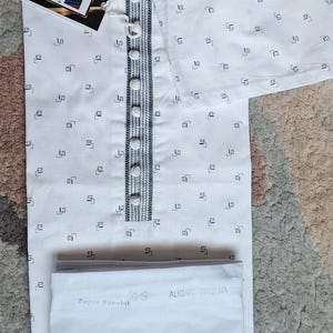 May include: White kurta pajama set with a small black geometric pattern. The kurta features a mandarin collar, button-down front, and decorative trim. The set includes matching pants. A tag reads "I.ELEGANT".