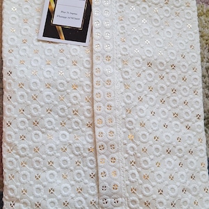 Puede incluir: Camisa blanca para hombre con un patr&oacute;n bordado en dorado. La camisa tiene un cuello mandar&iacute;n y cierre de bot&oacute;n. La etiqueta de la camisa dice "J. ELEGANT" e "I. ELEGANT WEAR".