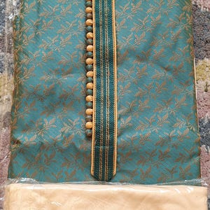 May include: Teal and gold patterned kurta pajama set. The kurta features a mandarin collar, decorative buttons, and a vertical stripe design. The text "I.ELEGANT" is visible on the collar. The pajama bottoms are a solid beige color.