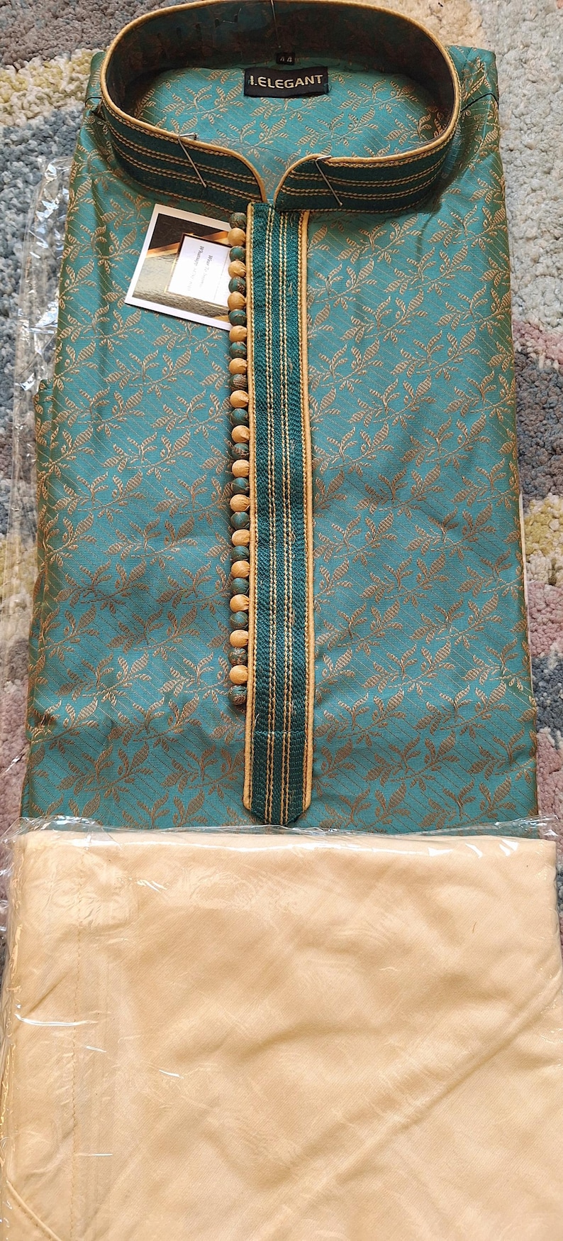 May include: Teal and gold patterned kurta pajama set. The kurta features a mandarin collar, decorative buttons, and a vertical stripe design. The text "I.ELEGANT" is visible on the collar. The pajama bottoms are a solid beige color.